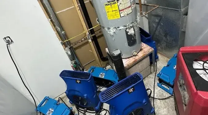 Air movers and a dehumidifier drying out a cramped water heater closet