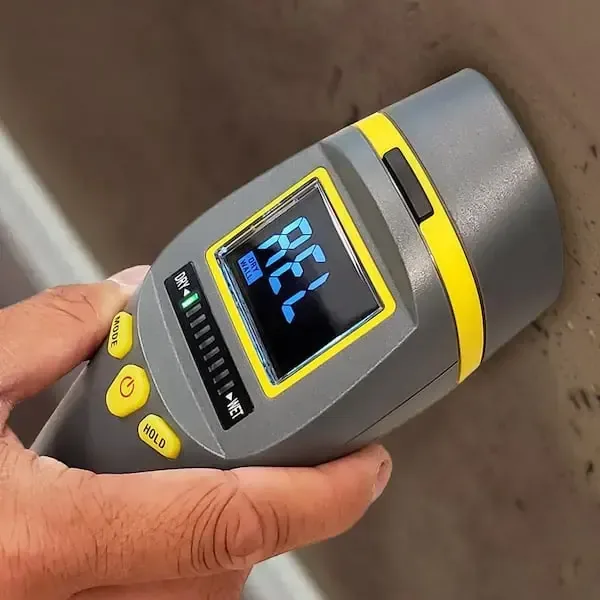 Pinless moisture meter pressed against a wet surface to log the reading